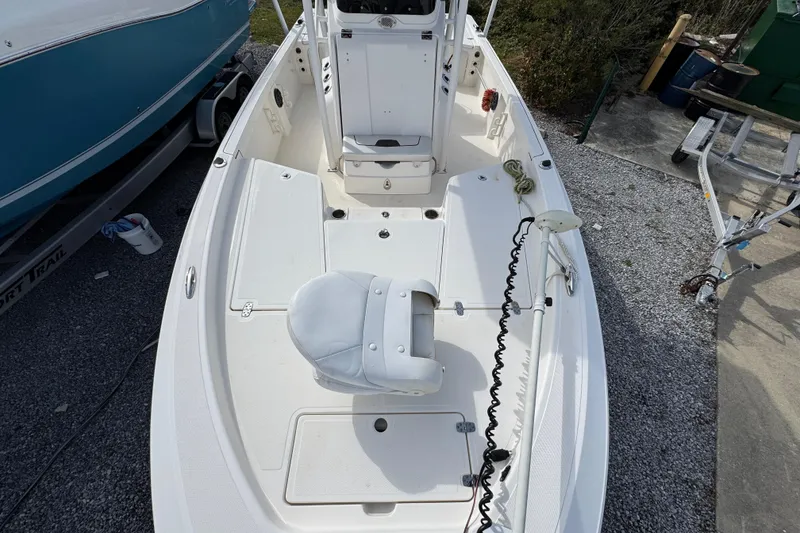 Slide: The Image of 2019 Wellcraft 221 Bay boat interior, featuring white seating and deck, parked on gravel. - 17
