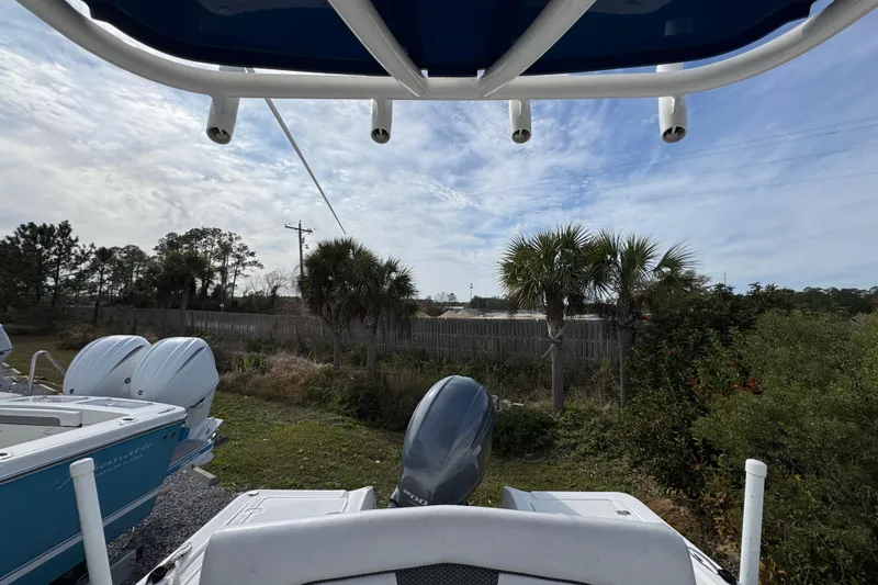 Slide: The Image of 2019 Wellcraft 221 Bay boat with dual engines, parked near palm trees under a cloudy sky. - 28