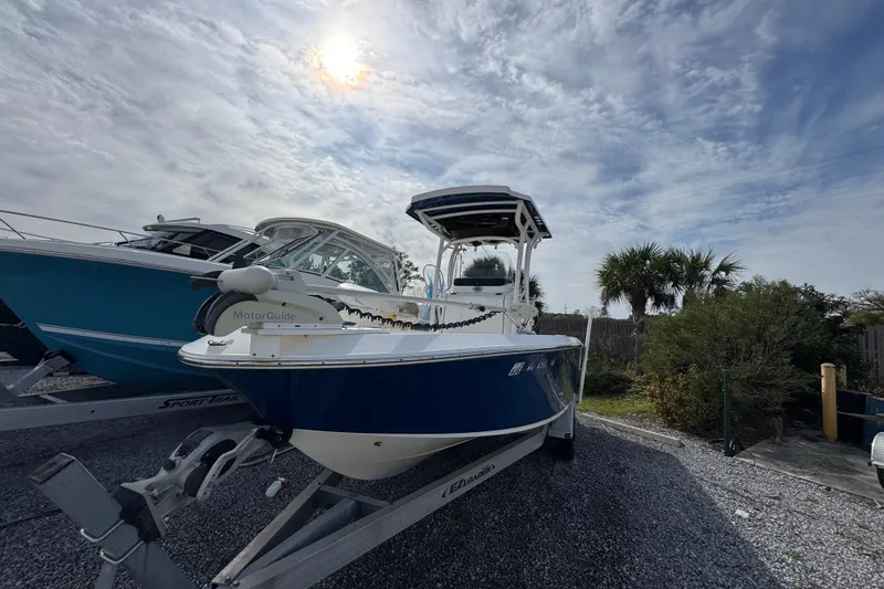 Slide: The Image of 2019 Wellcraft 221 Bay boat on trailer under cloudy sky, surrounded by trees. - 3