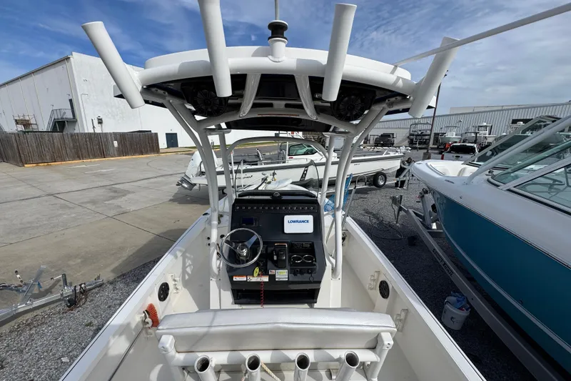 Slide: The Image of 2019 Wellcraft 221 Bay boat interior with steering console and rod holders, parked in a marina. - 30