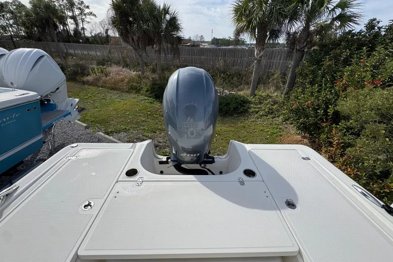Slide: The Image of 2019 Wellcraft 221 Bay boat with outboard motor, parked outdoors near palm trees. - 32