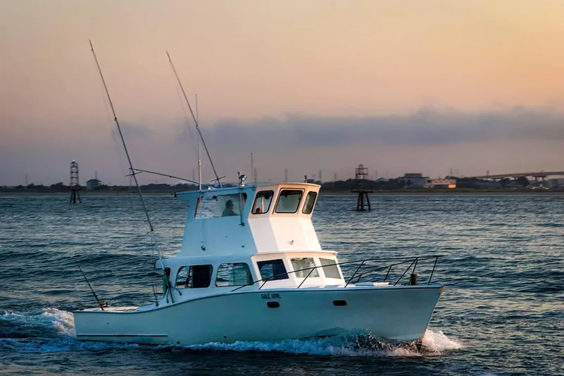 The Image of 1964 Myron Harris 35 Flybridge boat cruising at sunset on open water. - 0