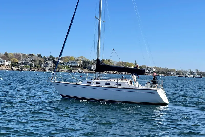 Slide: The Image of 1988 Tartan 28 sailboat on calm waters with coastal houses in the background. - 3