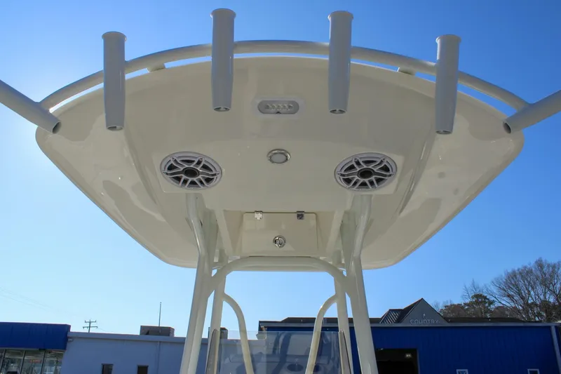 Slide: The Image of 2026 Pathfinder 2400 Open boat T-top with rod holders and speakers against blue sky. - 13