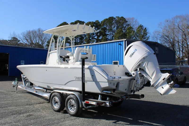 Slide: The Image of 2026 Pathfinder 2400 Open boat on trailer with Yamaha engine, parked near blue building. - 2
