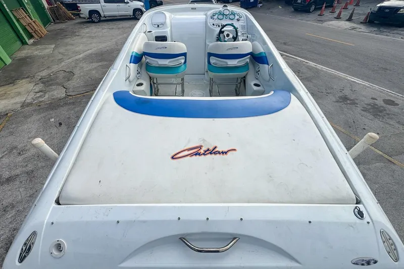 Slide: The Image of 1999 Baja 29 Outlaw speedboat with blue and white interior, parked on pavement. - 18