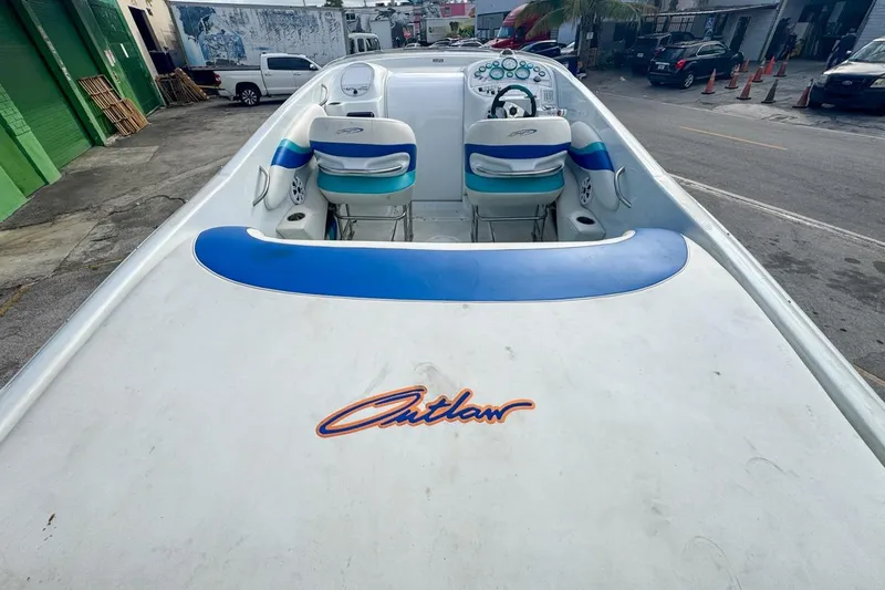Slide: The Image of 1999 Baja 29 Outlaw speedboat with blue and white interior, parked on urban street. - 22