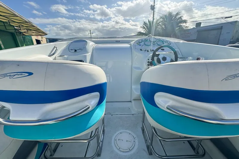 Slide: The Image of 1999 Baja 29 Outlaw boat cockpit with dual seats and steering wheel under a cloudy sky. - 33