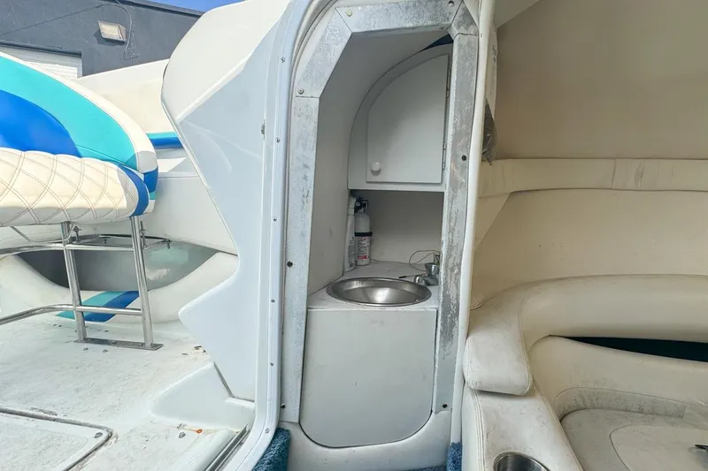 Slide: The Image of 1999 Baja 29 Outlaw boat interior with sink, seating, and blue-white upholstery. - 52
