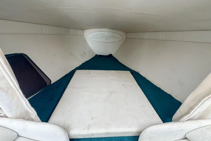 Slide: The Image of Interior cabin of a 1999 Baja 29 Outlaw boat with white and teal upholstery. - 56