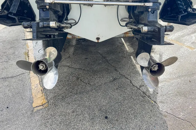 Slide: The Image of 1999 Baja 29 Outlaw boat propellers on wet pavement, showcasing dual outboard motors. - 6