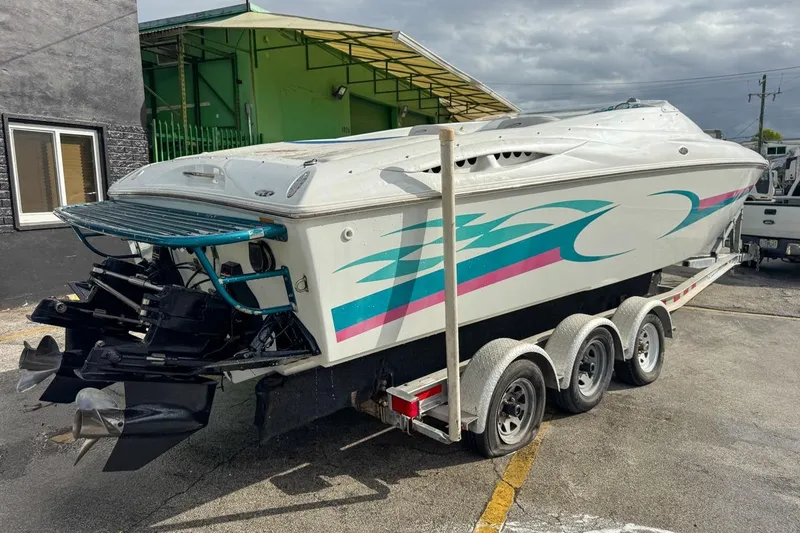 Slide: The Image of 1999 Baja 29 Outlaw speedboat on trailer with colorful graphics, parked outdoors. - 7