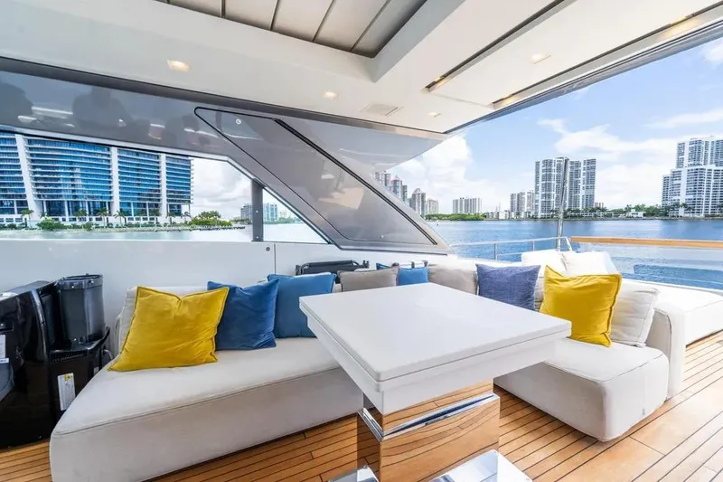 Slide: The Image of Luxurious 2021 Sanlorenzo SX76 yacht interior with plush seating and vibrant cushions, overlooking waterfront cityscape. - 11