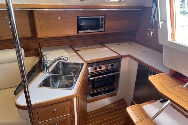 Slide: The Image of 2016 Catalina 385 yacht kitchen with wood cabinetry, stainless steel sink, oven, and microwave. - 2