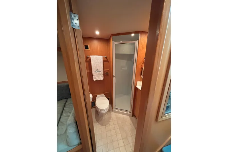 Slide: The Image of Compact bathroom in a 2006 Dixon 52 yacht, featuring shower, toilet, and wooden accents. - 9