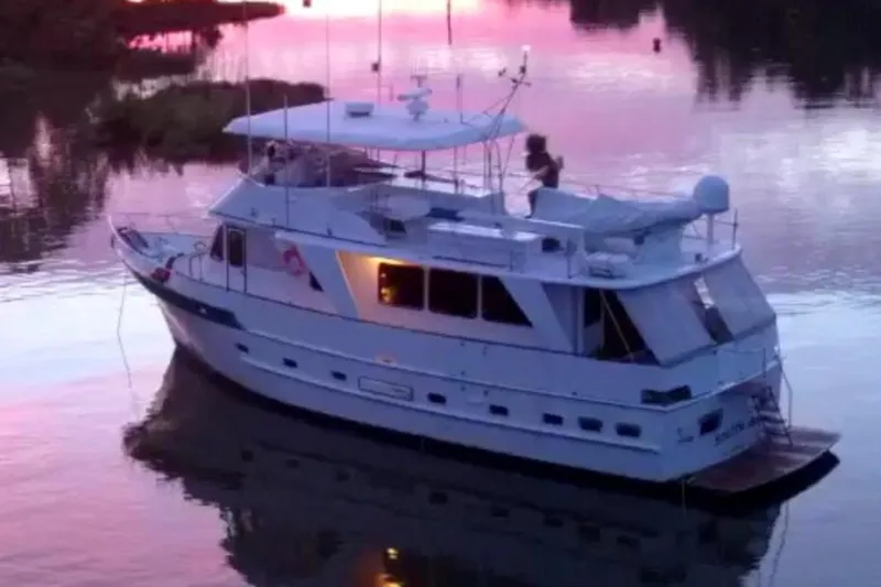 Slide: The Image of 1982 DeFever 52 Offshore Cruiser on serene water at sunset. - 3