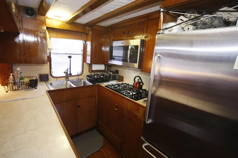 Slide: The Image of 1982 DeFever 52 Offshore Cruiser kitchen with wooden cabinets, stainless steel appliances, and double sink. - 39