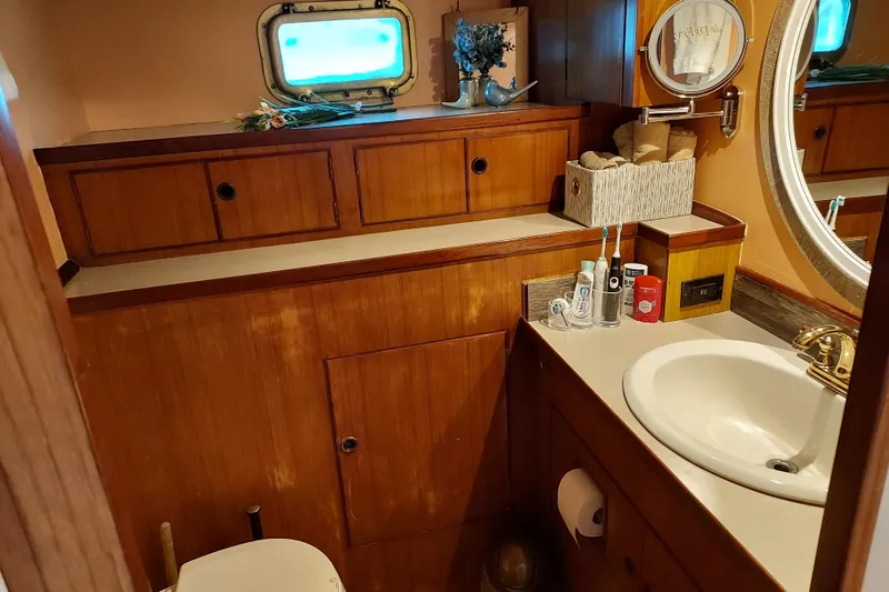 Slide: The Image of Bathroom interior of 1982 DeFever 52 Offshore Cruiser with wooden cabinetry and porthole window. - 52