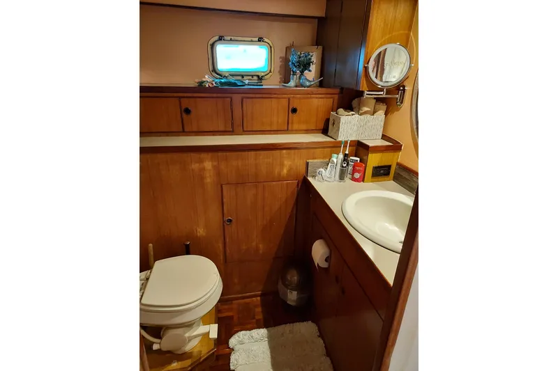 Slide: The Image of 1982 DeFever 52 Offshore Cruiser bathroom with wooden cabinetry and porthole window. - 54