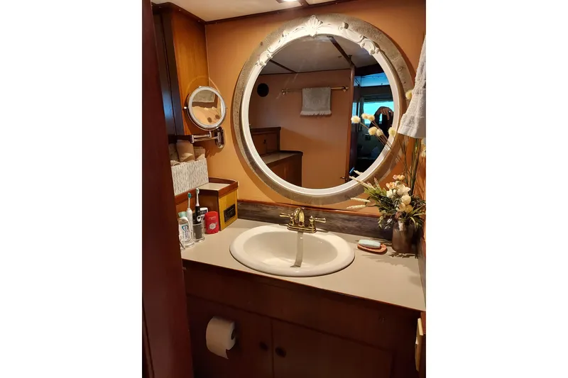 Slide: The Image of Elegant bathroom vanity on 1982 DeFever 52 Offshore Cruiser with round mirror and floral decor. - 55