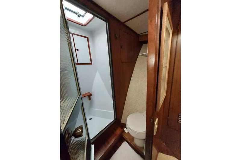 Slide: The Image of 1982 DeFever 52 Offshore Cruiser bathroom with shower and toilet, featuring wooden accents. - 62