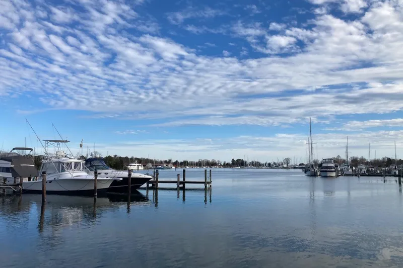 Slide: The Image of Boats docked at a serene marina under a partly cloudy sky. - 74