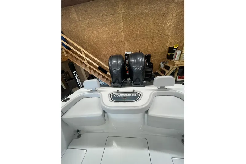Slide: The Image of 2024 Contender 24 Sport boat interior with dual engines in a garage setting. - 12