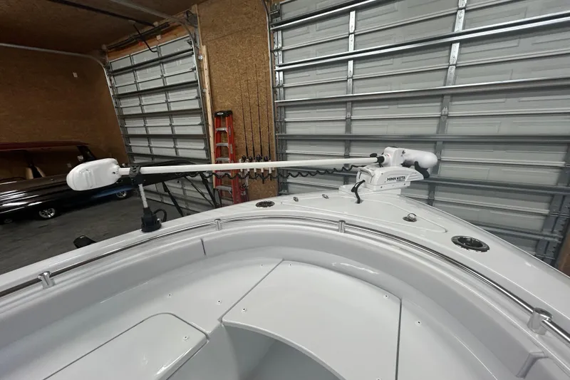 Slide: The Image of 2024 Contender 24 Sport boat with Minn Kota trolling motor in a garage setting. - 25
