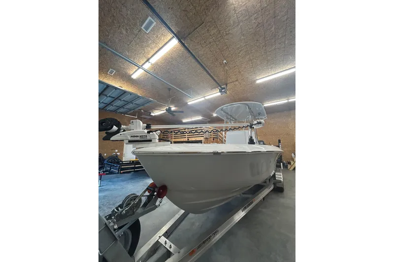 Slide: The Image of 2024 Contender 24 Sport boat in a garage, featuring a Minn Kota trolling motor. - 34