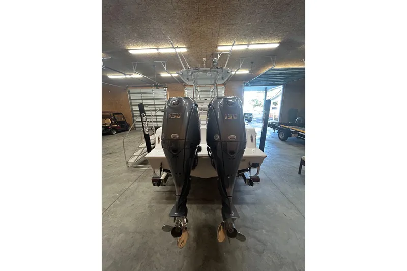 Slide: The Image of 2024 Contender 24 Sport boat with dual 150 horsepower engines in a garage. - 4