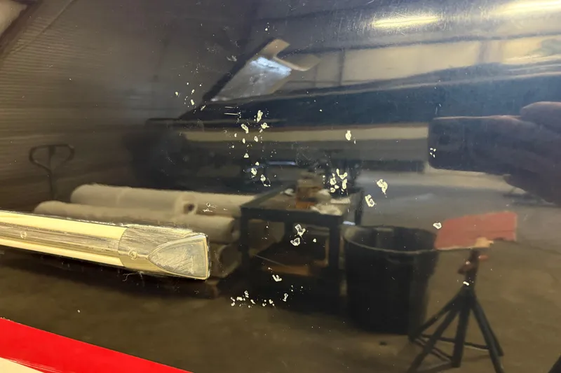 Slide: The Image of 2019 Chris-Craft Catalina 26 boat hull with visible scratches and reflections in a garage. - 16