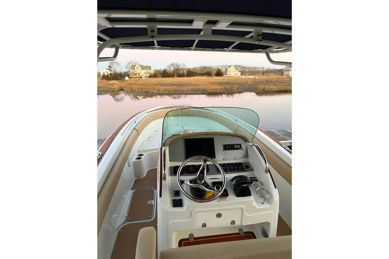 Slide: The Image of 2019 Chris-Craft Catalina 26 boat interior with steering wheel and control panel, docked by a serene lake. - 4