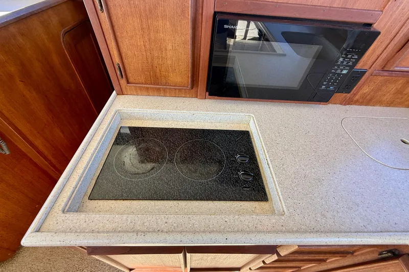 Slide: The Image of 1985 Chris-Craft 382 Commander kitchen with stove and microwave, featuring wooden cabinetry. - 12