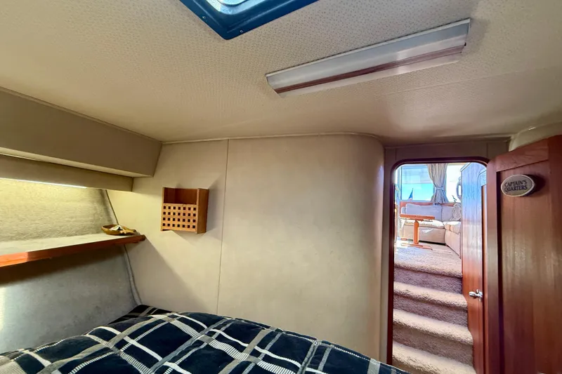 Slide: The Image of 1985 Chris-Craft 382 Commander cabin interior with bed, wooden accents, and cozy decor. - 26