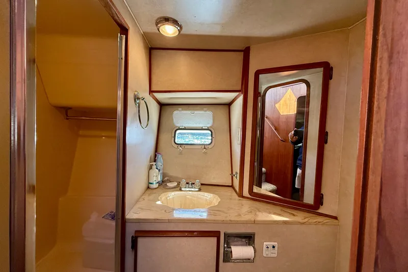 Slide: The Image of Bathroom interior of 1985 Chris-Craft 382 Commander yacht, featuring sink, mirror, and porthole window. - 27