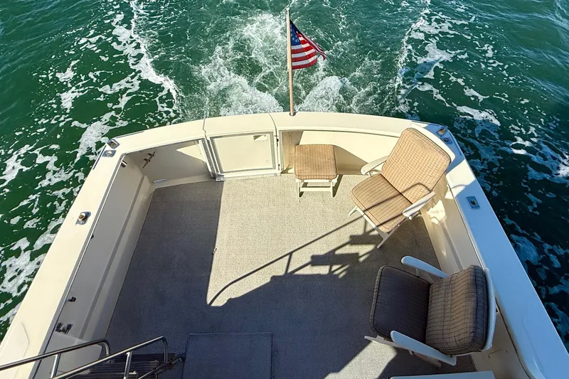 Slide: The Image of 1985 Chris-Craft 382 Commander boat deck with chairs and American flag on water. - 38