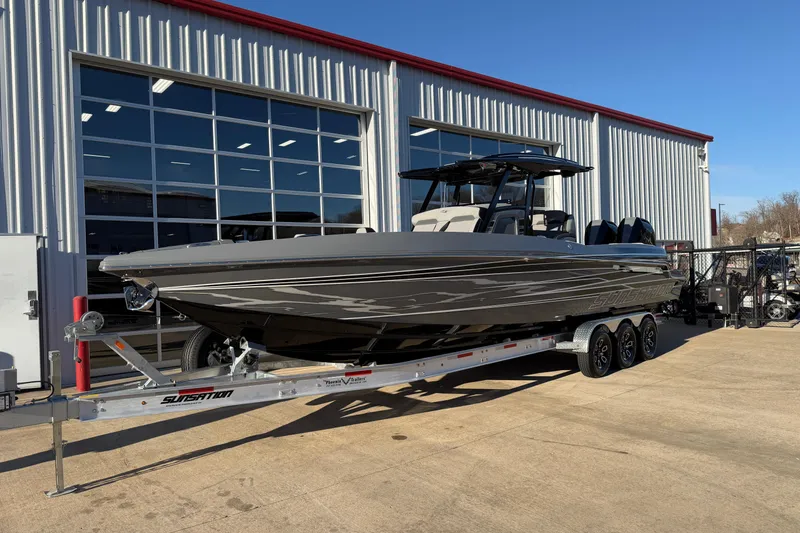Slide: The Image of 2026 Sunsation 32CCX boat on trailer outside a large garage. - 3