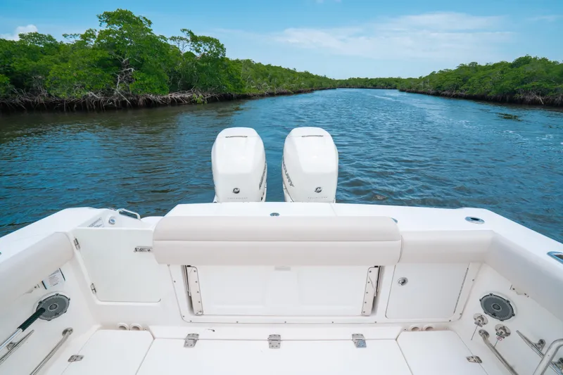 Slide: The Image of 2019 Boston Whaler 330 Outrage on a serene river with lush greenery. - 19