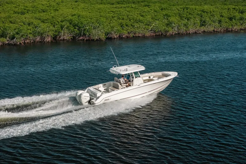 Slide: The Image of 2019 Boston Whaler 330 Outrage cruising on a scenic waterway near lush greenery. - 25