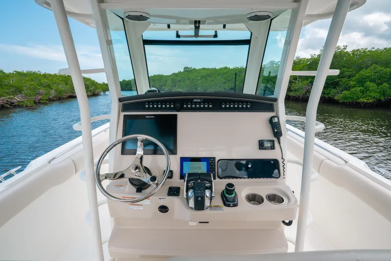 Slide: The Image of 2019 Boston Whaler 330 Outrage helm with modern controls and scenic waterway view. - 4