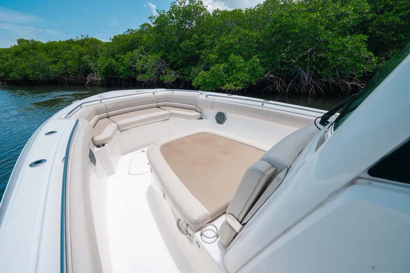 Slide: The Image of 2019 Boston Whaler 330 Outrage boat interior with cushioned seating near lush mangroves. - 8
