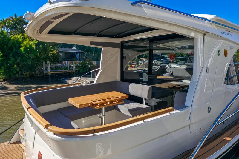 Slide: The Image of 2026 Marex 330 Scandinavia yacht with elegant outdoor seating and wooden table. - 7