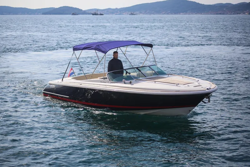 Slide: The Image of 2004 Chris-Craft Corsair 28 boat cruising on open water with a blue canopy. - 1