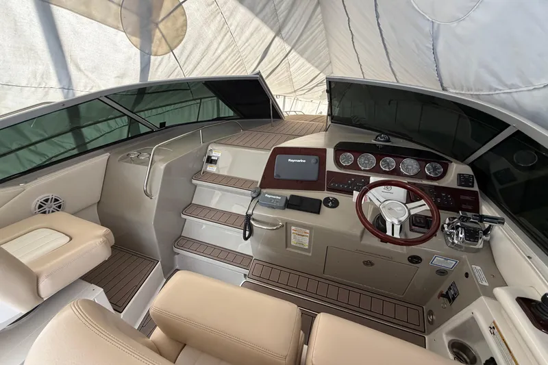 Slide: The Image of 2014 Sea Ray 370 Sundancer helm with modern controls and beige seating under a canopy. - 34