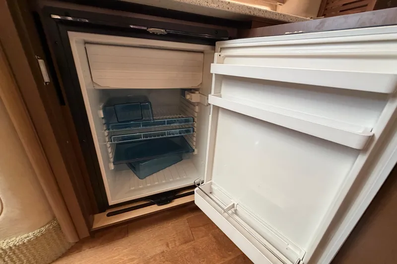 Slide: The Image of Open refrigerator inside 2014 Sea Ray 370 Sundancer yacht, showcasing interior storage space. - 52