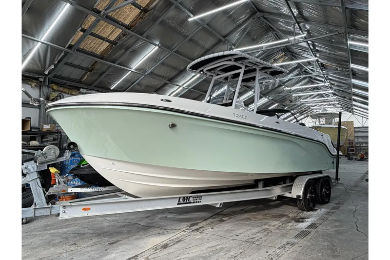 The Image of 2023 Bayliner Trophy T24CC boat on trailer in a metal-roofed storage facility. - 0