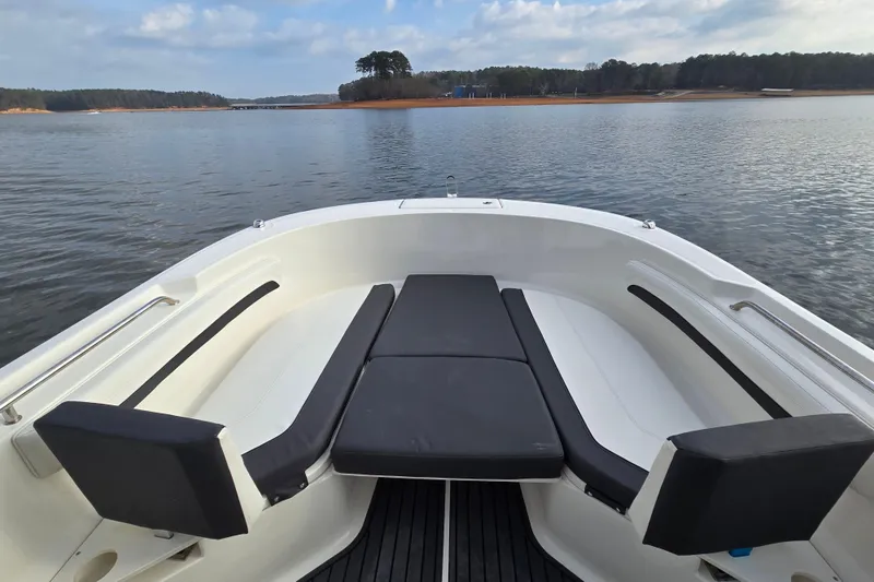Slide: The Image of 2023 Bayliner Trophy T24CC boat interior with cushioned seating on calm water. - 11