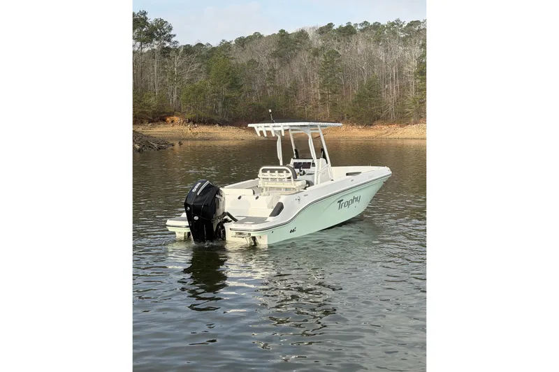 Slide: The Image of 2023 Bayliner Trophy T24CC boat on a calm lake with forested shoreline. - 6