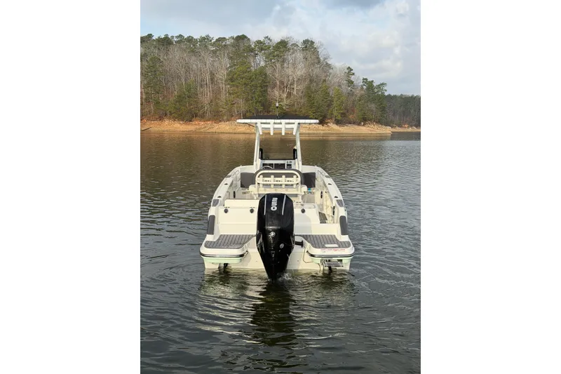 Slide: The Image of 2023 Bayliner Trophy T24CC boat on a calm lake with forested shoreline. - 7