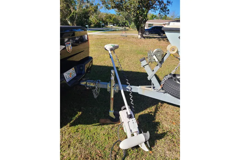 Slide: The Image of 1994 Key West 1900 Sportsman boat trailer hitched to a truck in a grassy area. - 17